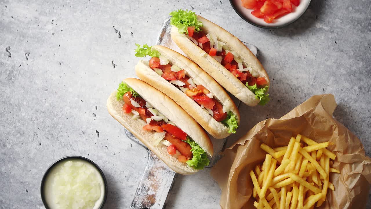 Tre hot dog alla griglia con salsiccia messi su una tavola da taglio in legno