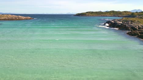 Lofoten-island-sea-waves-flight,-drone-flight-over-crystal-clear-turquoise-arctic-water-on-the-island-of-skrova-in-the-lofoten-islands