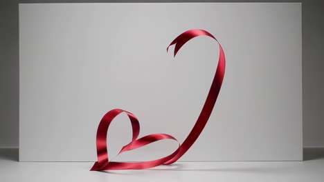 red ribbon forming a heart shape against a white background