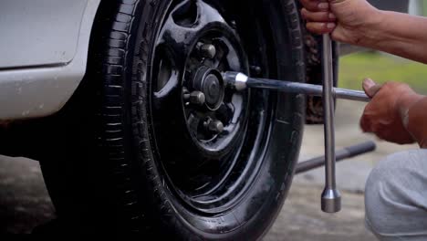 close up shot of hand man use wrench to fit the nut of car rim - replace car wheel process