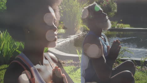 animación de puntos de luz sobre una pareja afroamericana haciendo yoga, meditando, en cámara lenta