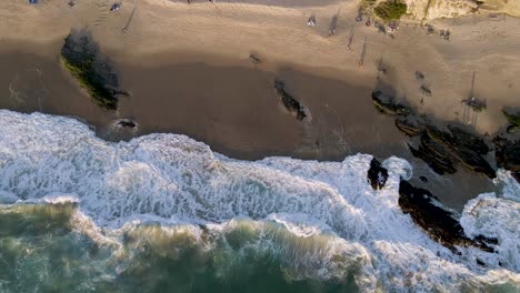Waves-breaking-on-Laguna-Beach-at-sunset,-California-coast,-aerial-top-down-view