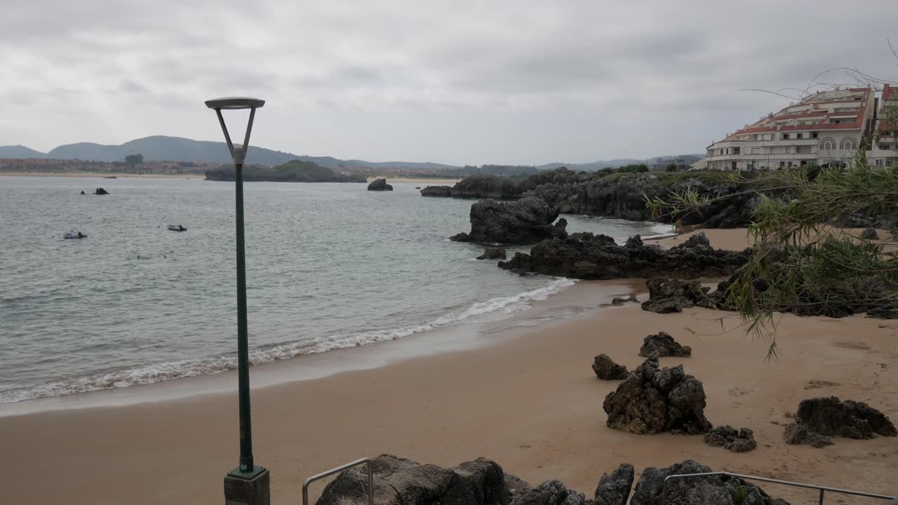 Calm beach view with rocks and cloudy skies at Quejo beach, Cantabria, Spain