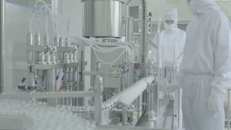 production line in sterile environment with lab workers in washing gloves on the background. scientist hand working in laboratory. science, chemistry and medicine concept. pharmacist making medicines
