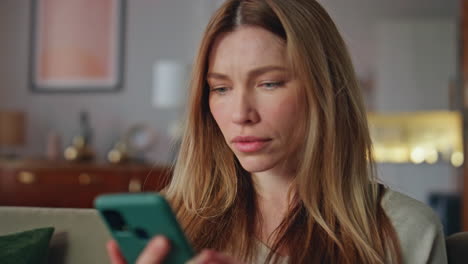 Shocked girl looking mobile phone in home closeup. Woman reading smartphone