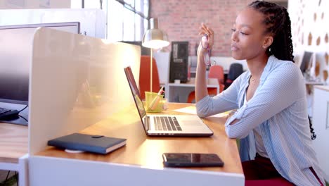african american casual businesswoman making video call using laptop in office, slow motion