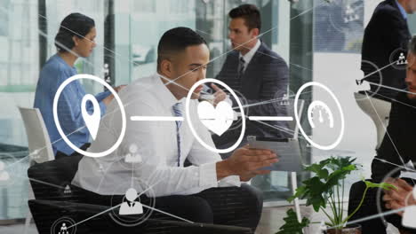animation of network of digital icons over two diverse businessmen discussing over tablet at office