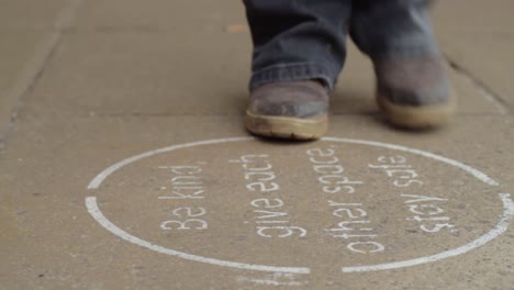 bottes marchant sur un panneau de distanciation sociale sur le trottoir de la rue