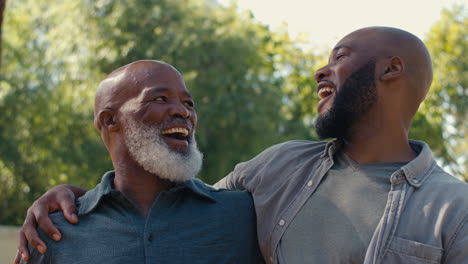 Portrait-Of-Loving-Senior-Father-With-Adult-Son-Standing-Outdoors-In-Garden-Park-Or-Countryside