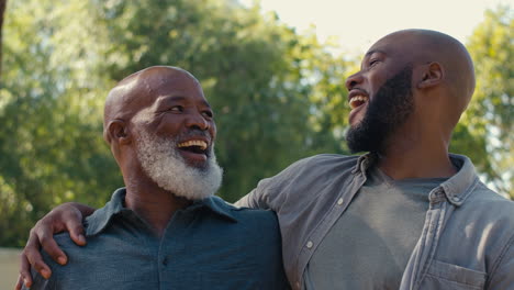 portrait of loving senior father with adult son standing outdoors in garden park or countryside