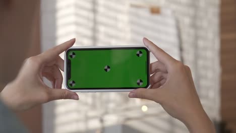 chica usando un teléfono inteligente con pantalla verde en la sala de estar
