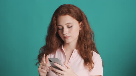 Redheaded-girl-in-front-of-camera-on-turquoise-background.