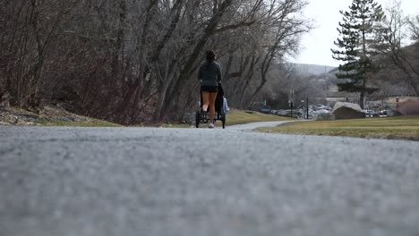 Female-Runner-Pushing-Jogging-Stroller-on-Outdoor-Path---Ground-Level-View