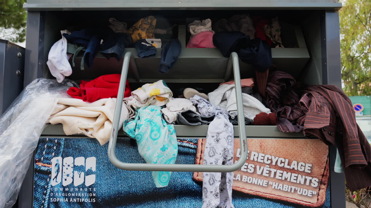 Antibes, France - May 17, 2025: Close up of an overflowing clothing donation bin