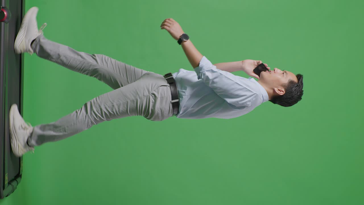 사이드 뷰 아시아 사업가의 전체 몸은 스튜디오에서 녹색 화면 배경에서 는 동안 휴대 전화로 이야기