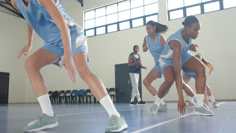 Practicing dribbling drills, female athletes playing basketball in school gymnasium