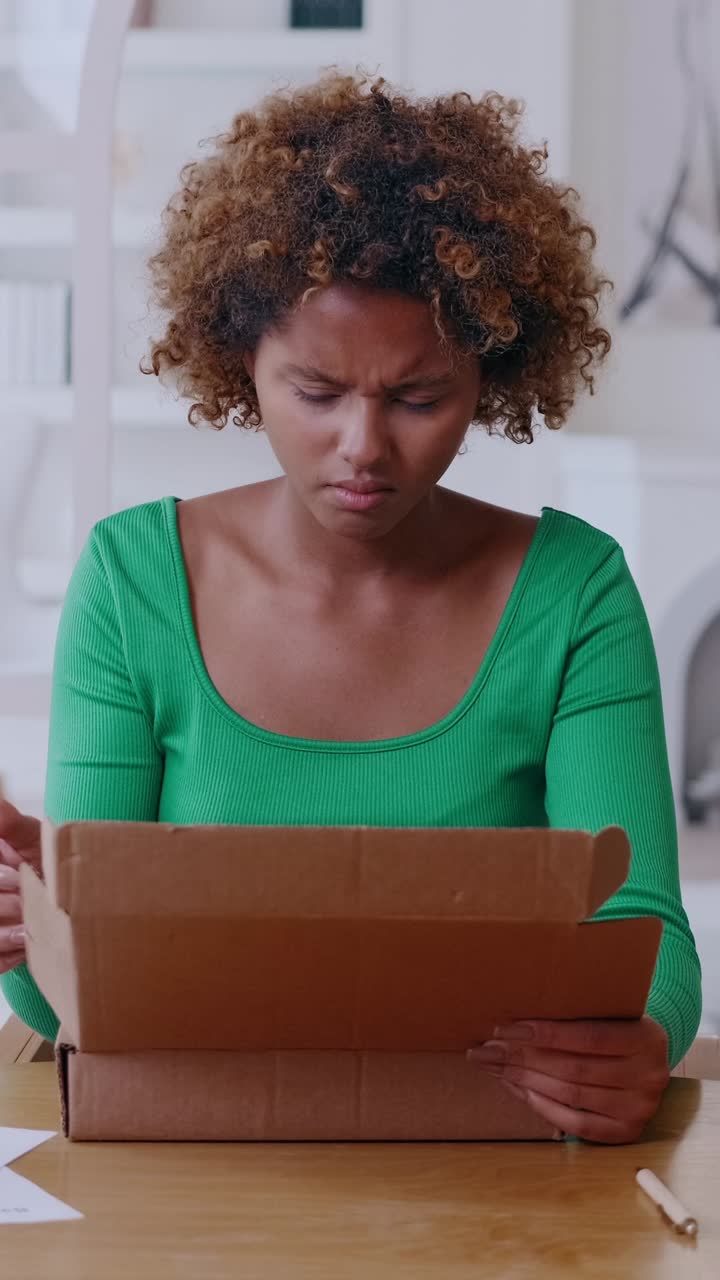 Young woman unpacking a cardboard box at a wooden desk