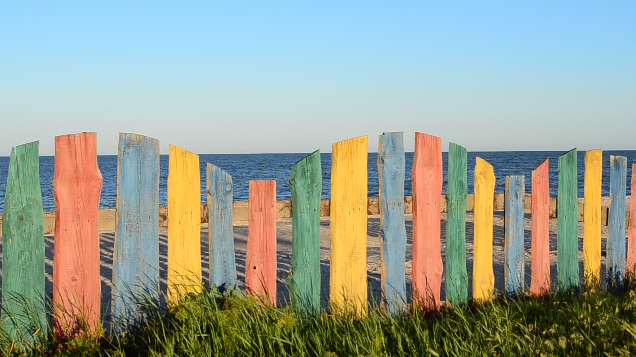 Recinzione multicolore sulla spiaggia. Recinzione e cielo, estate.