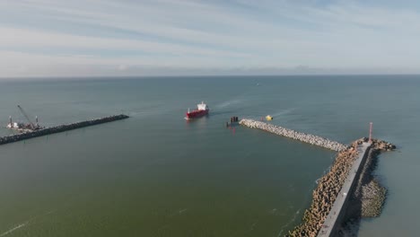 vista aérea: un carguero rojo navega a través de las puertas del puerto de la ciudad de klaipeda