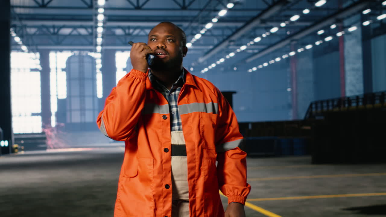 Black operator talks through walkie talkie and monitoring metal fabrication