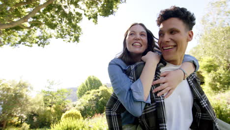 pareja feliz jugando a espaldas y caminando en el jardín soleado, copiar el espacio, en cámara lenta