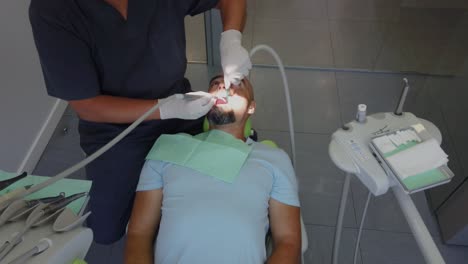 a man is laying at the dentist while the doctor works in his mouth