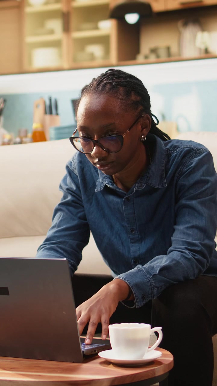 Vertical Video Black woman working remotely from home setup and drinking coffee