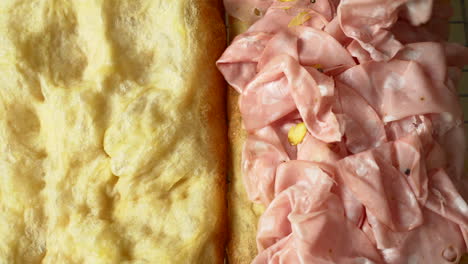 the chef is placing delicious italian mortadella on top of a crusty and airy pizza sandwich