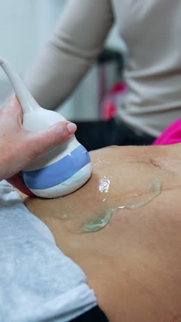 doctor's hand moving the device by the belly of a woman. ultrasound check up of pregnancy. vertical video