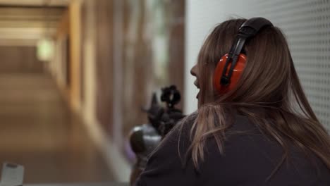 Woman-with-rifle-in-hands-at-shooting-range-with-target,-excited-and-surprised