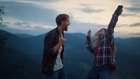 fun family celebrate dance fun in dusk mountains. young couple move outside.