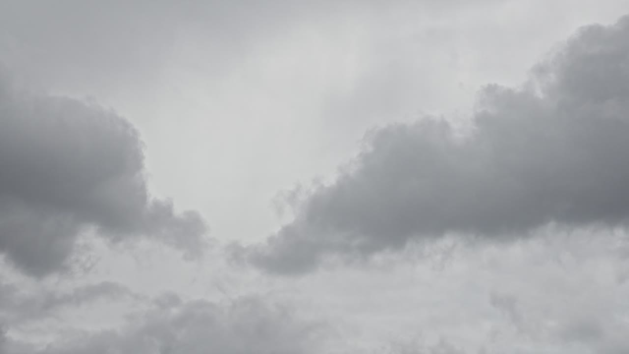 Dark grey clouds gather fast in sky, forming rain clouds in moody time lapse sky