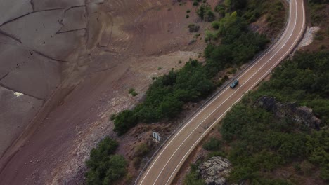 Aerial-view-of-a-car-cruising-along-roads-near-the-lake