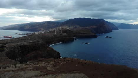 Drone-view-captures-Miradouro-Ponta-Rosto-in-the-morning-under-a-dark-sky,-showcasing-the-tranquil-beauty-of-the-cliffside-viewpoint-amidst-natural-surroundings