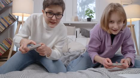 Mother and Daughter Playing Video Games on a Bed