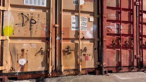 Alte-Rostige-Metallbehälter-Für-Verlassene-Waren,-Die-In-Lagerräume-Für-Die-Werkzeuge-Und-Utensilien-Der-Fischer-Im-Hafen-Umgewandelt-Wurden,-Beschreibende-Aufnahme-Nach-Oben