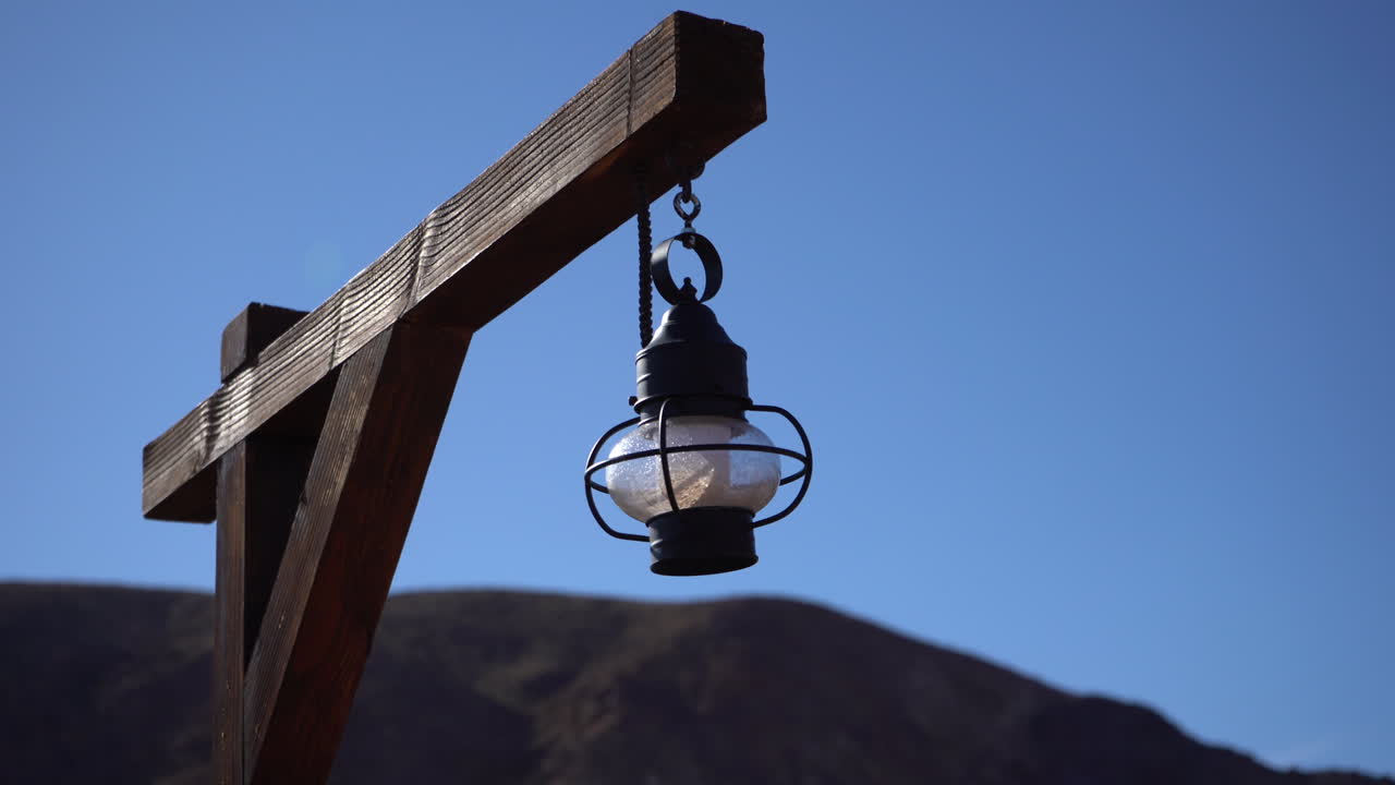 Lanterna vintage appesa a un palo di legno su uno sfondo di cielo blu