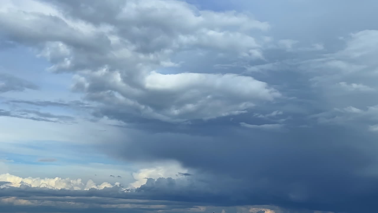 Cloud patterns over a vast blue sky. Fluffy clouds drift through a clear blue sky, showcasing a blend of various shades and textures during daytime