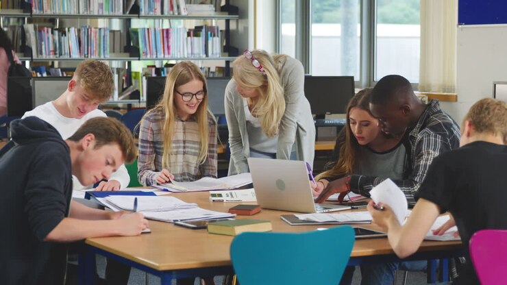 Female Teacher Working With College Students In Library