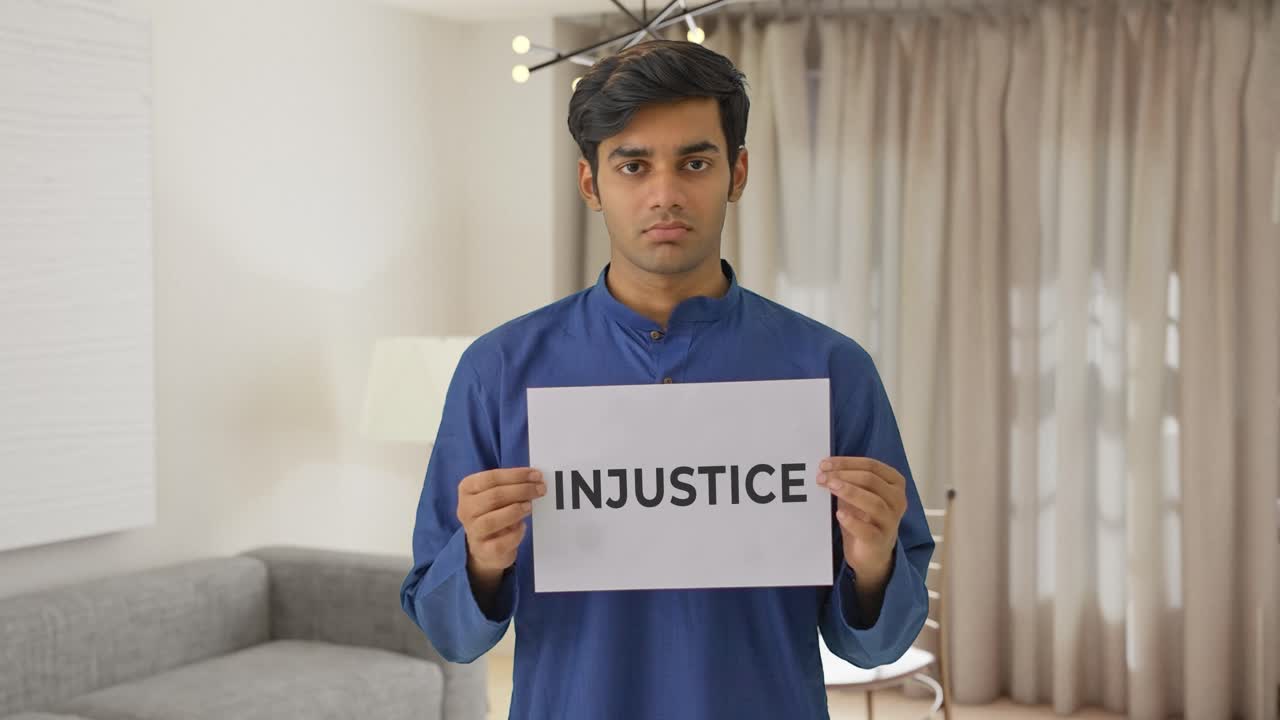 Sad Indian boy holding INJUSTICE banner