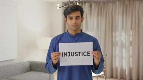 sad indian boy holding injustice banner