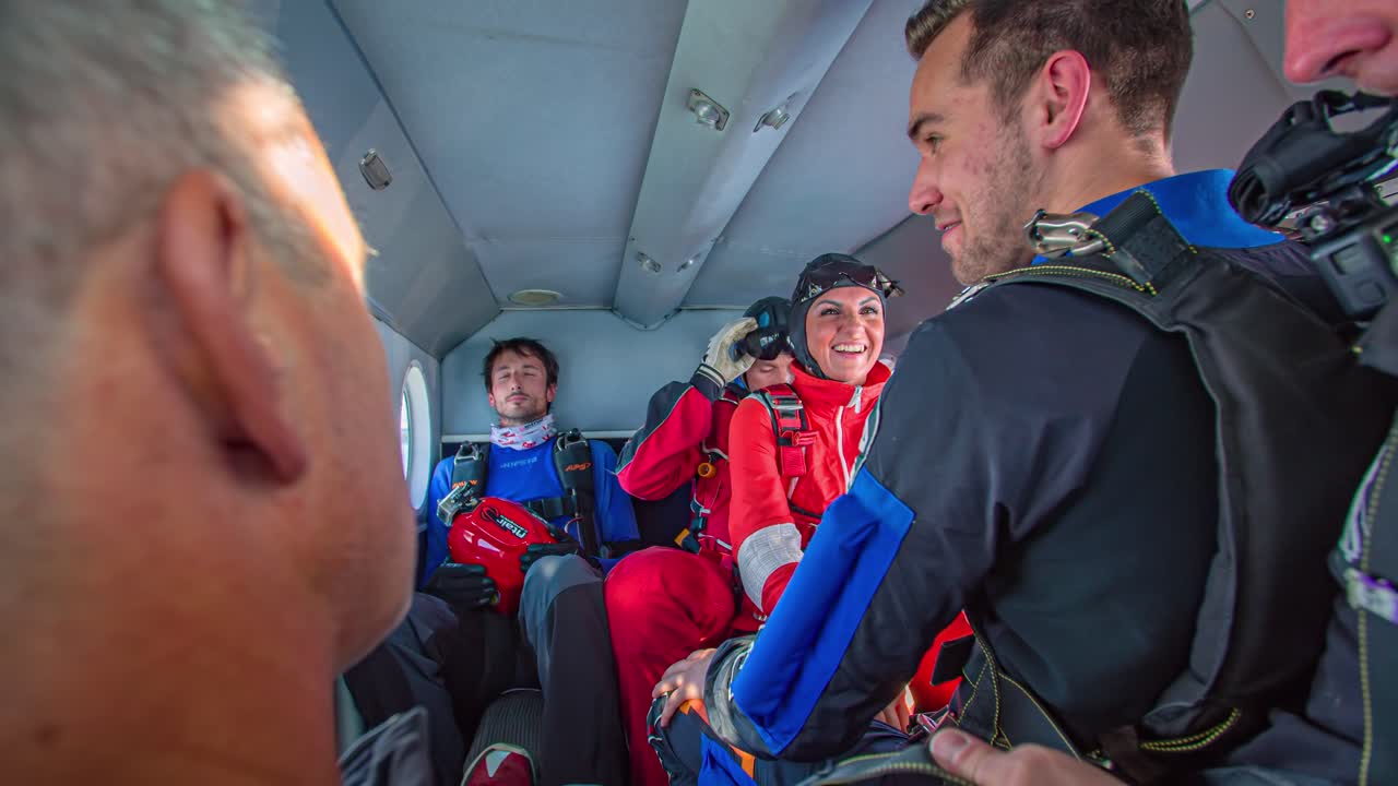 Group Of Skydivers Laughing And Preparing In Cockpit Of Plane Before Jump