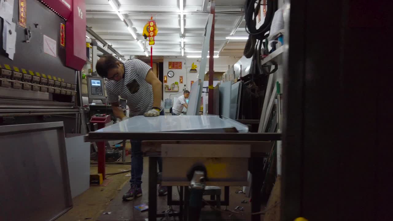 People work on iron sheets in a dusty workshop in London