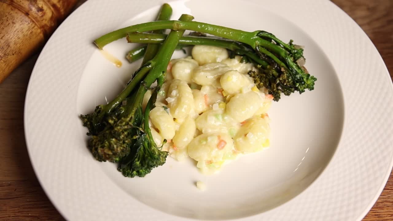 Gnocchi with Creamy Sauce and Broccolini Served on a White Plate