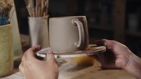 mujer joven presionando el pedazo de arcilla a un borde del mango y una taza