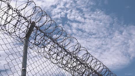 Medium-Shot-of-a-Barbed-Wire-Fence-with-Fluffy-Clouds-in-the-Background