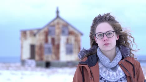 focus change between young girl with hair waving in the wind and rusty house in the background.