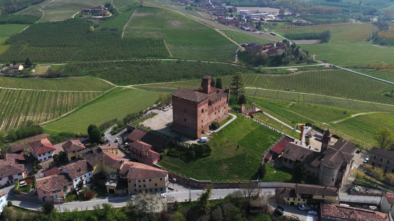 A trucking shot video showcasing the beautiful Grinzane Cavour castle, surrounded by scenic vineyards and a charming village, aerial view of the rural landscape in Italy