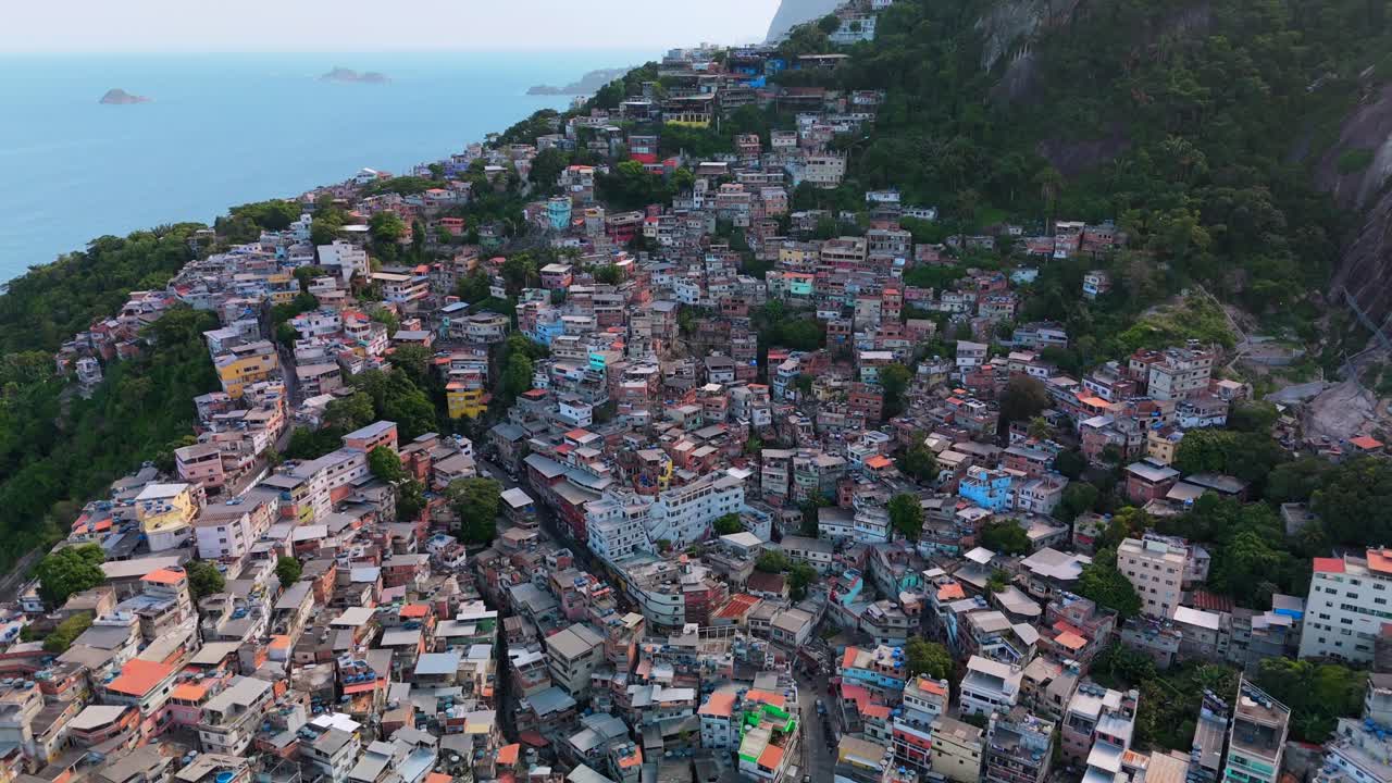 Drone pull-back shows Favela Vidigal's dense hillside homes above Rio's coast