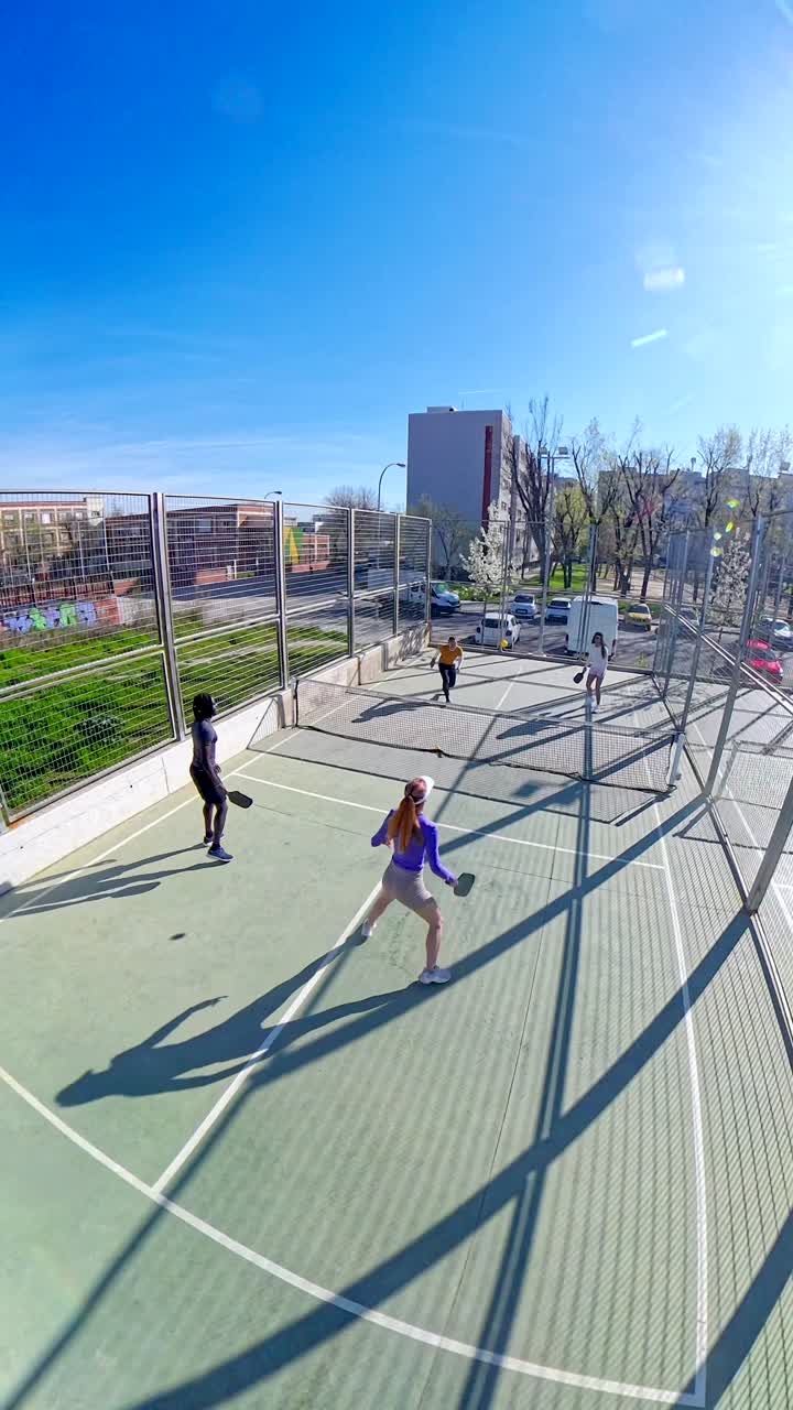 Quattro persone che giocano a padel su un campo all'aperto in una giornata di sole